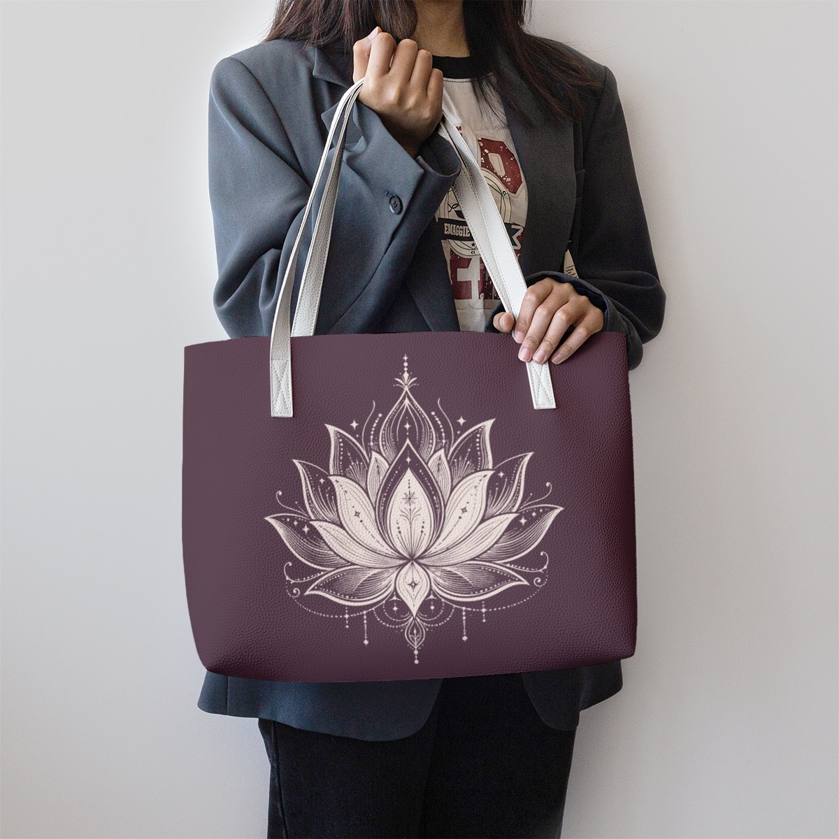 Plum tote bag with white straps and lotus graphic, shown carried by hand